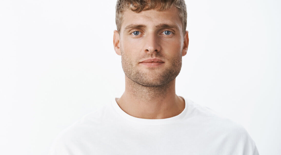 waist-up-shot-handsome-calm-blond-blue-eyed-guy-with-bristle-white-t-shirt-looking-front-with-relaxed-carefree-facial-expression-posing-gray-wall-looking-sincere-chill 1-1